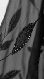 Close-up of an embroidered leaf with small black bead accents on chiffon